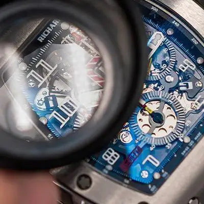 Blue and silver richard mille watch with exposed mechanical movement.