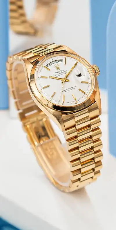 Gold rolex day-date wristwatch with a white dial and fluted bezel.