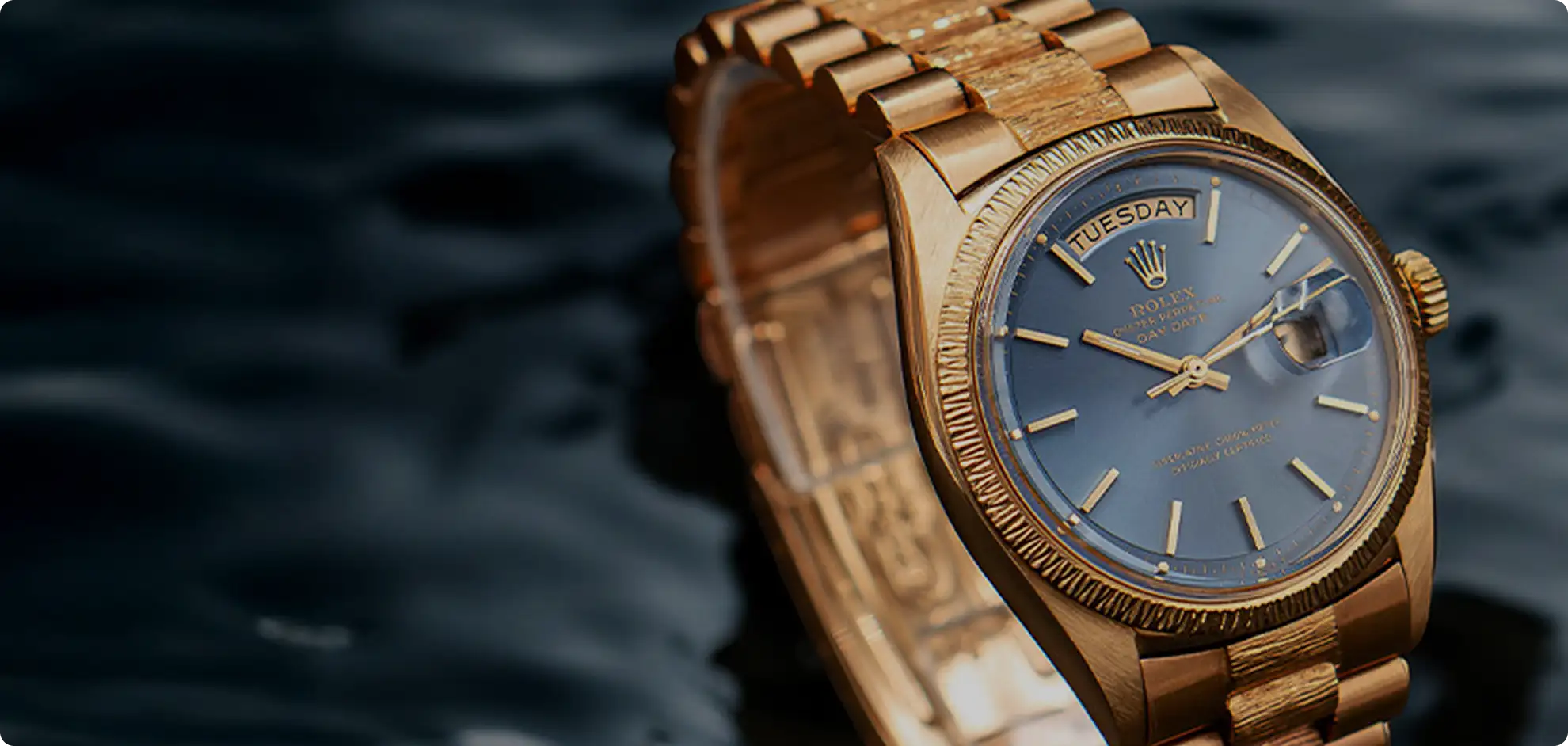 Gold-tone rolex day-date wristwatch with a blue dial and fluted bezel.