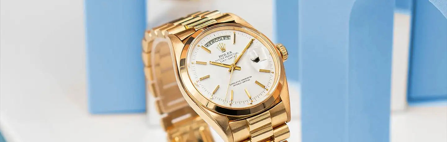 Gold-tone rolex day-date wristwatch with a white dial, gold hour markers and hands, and an integrated bracelet.