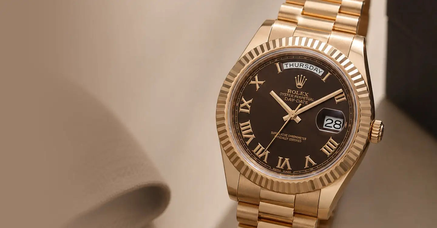 A luxurious gold-tone rolex day-date watch with a dark brown dial, roman numeral hour markers, and a fluted bezel.