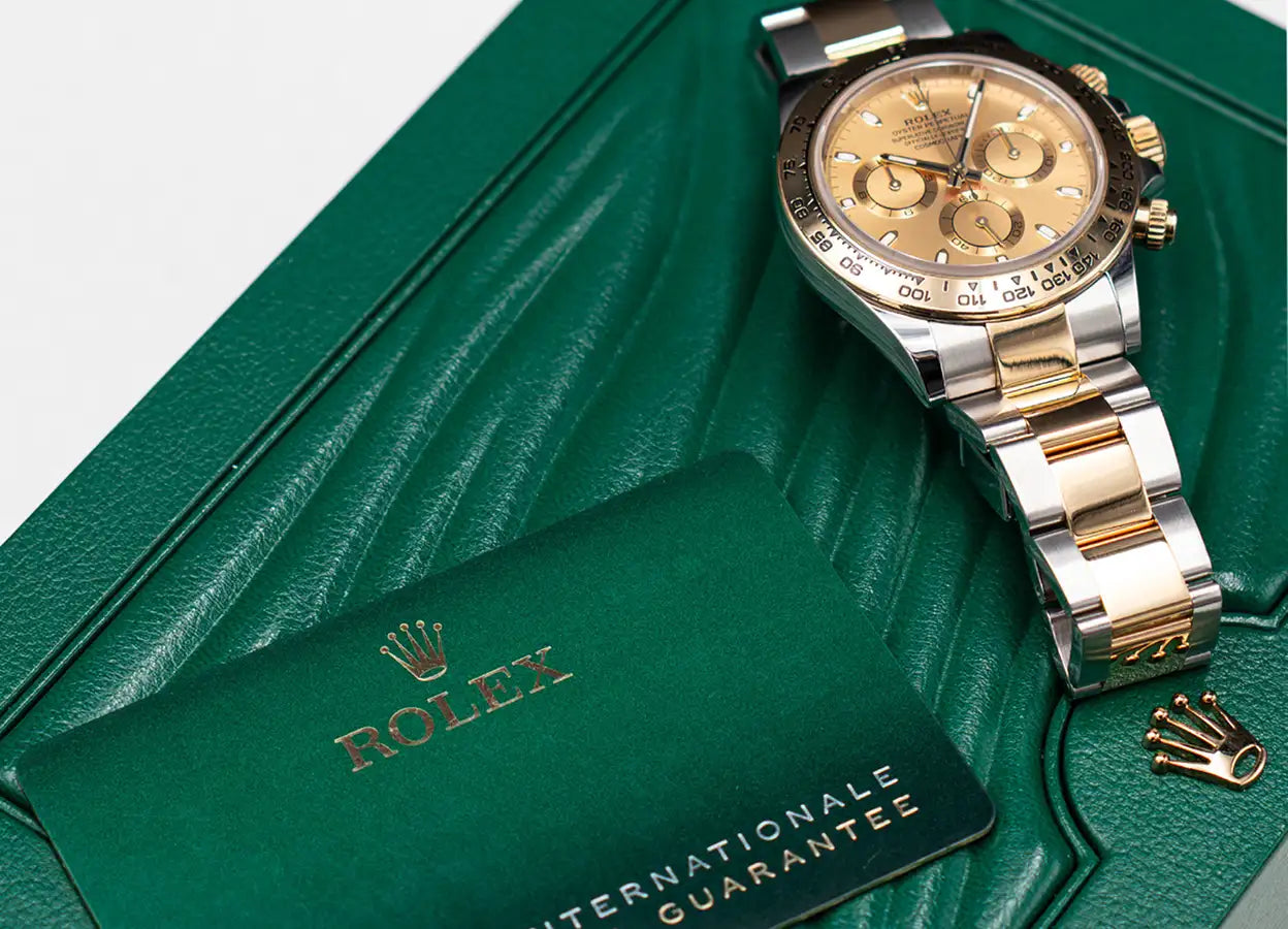 A luxurious two-tone gold and silver rolex daytona watch with a champagne-colored dial, displayed on its signature green leather box.