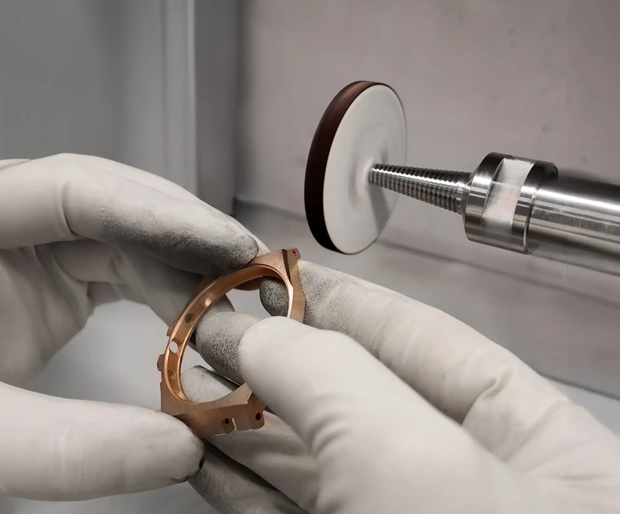 A polished rose gold watch case being refined by a precision polishing tool.