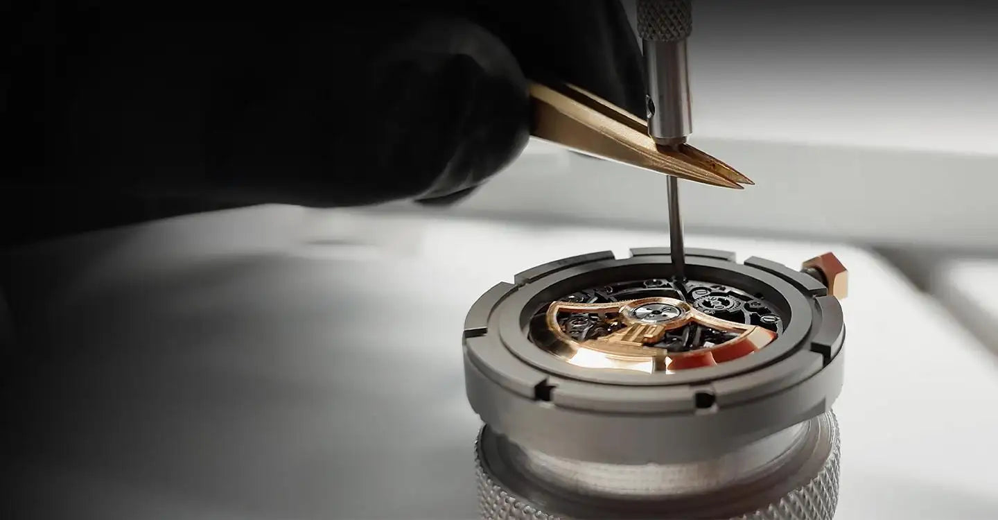 A precision-engineered watch movement with intricate golden gears and a polished metallic casing, being carefully adjusted by a technician using fine-tipped tools.