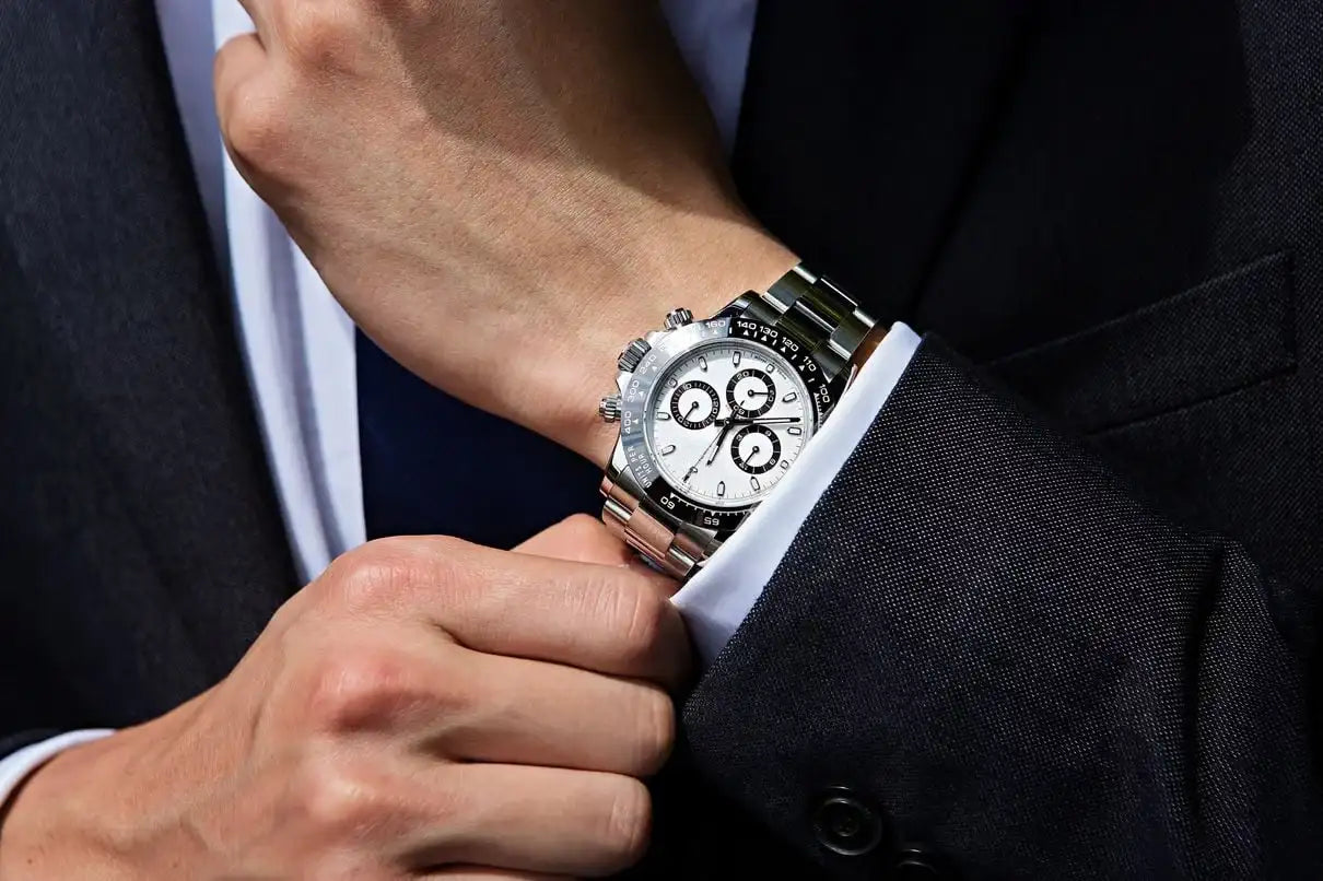 A sleek silver stainless steel rolex daytona watch with a white dial and black subdials, worn on a man’s wrist.