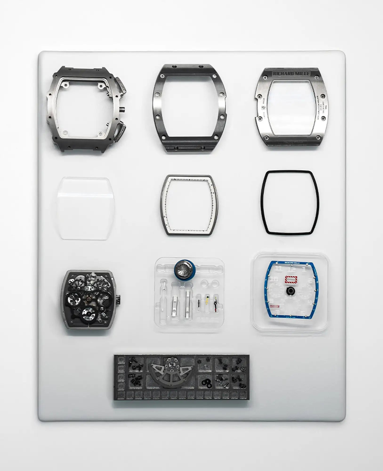 A sleek, square-shaped richard mille watch case assembly with a dark gray metallic finish and precise engineering details.