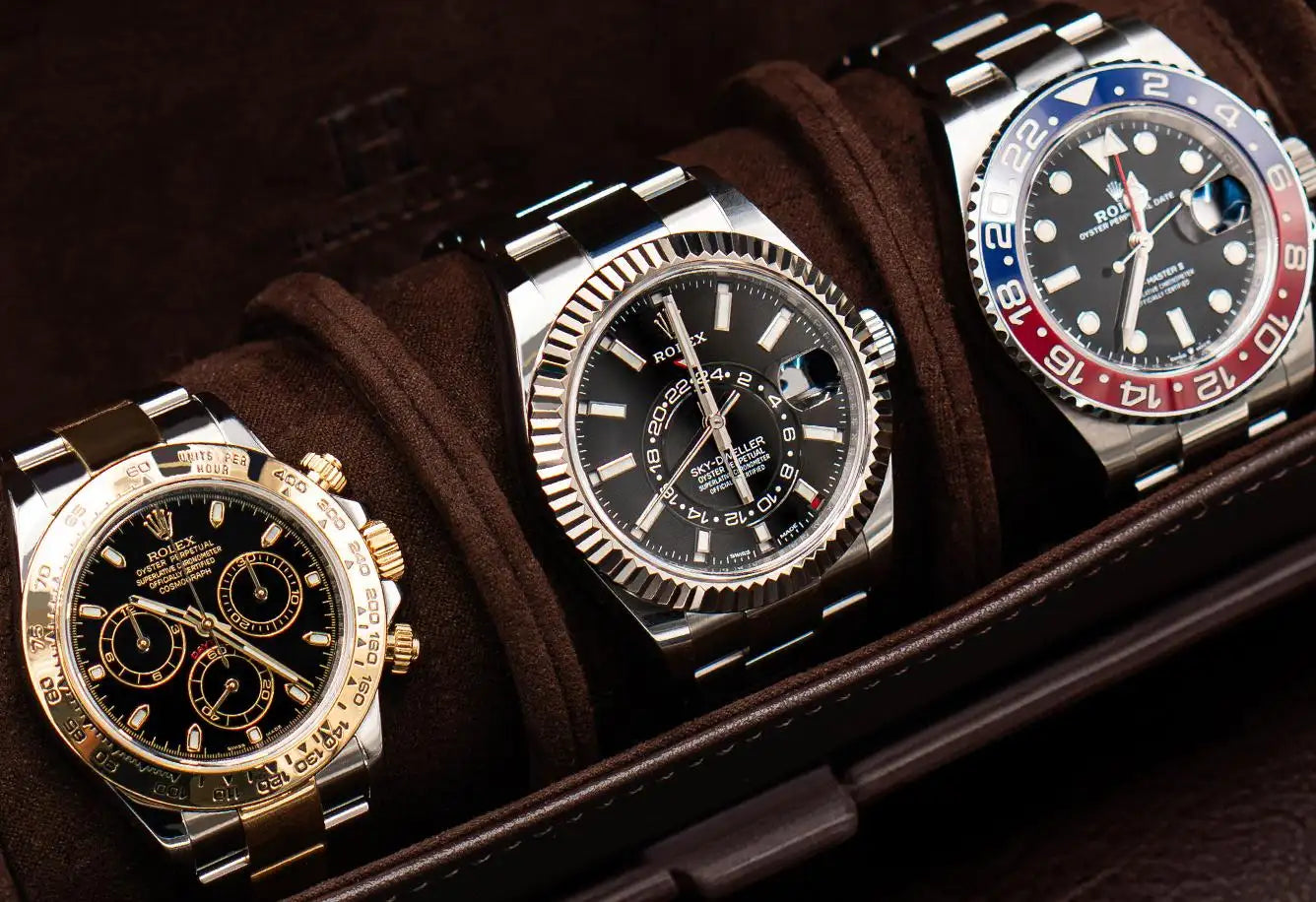 Three luxury rolex watches, featuring stainless steel and gold accents with black dials and distinctive bezels.